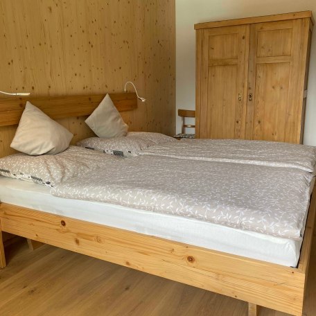 Das Balkonzimmer mit Doppelbett 180 X 200 und einem rustikalen Kleiderschrank, beides aus alter Fichte, © im-web.de/ Tourist-Information Bayrischzell